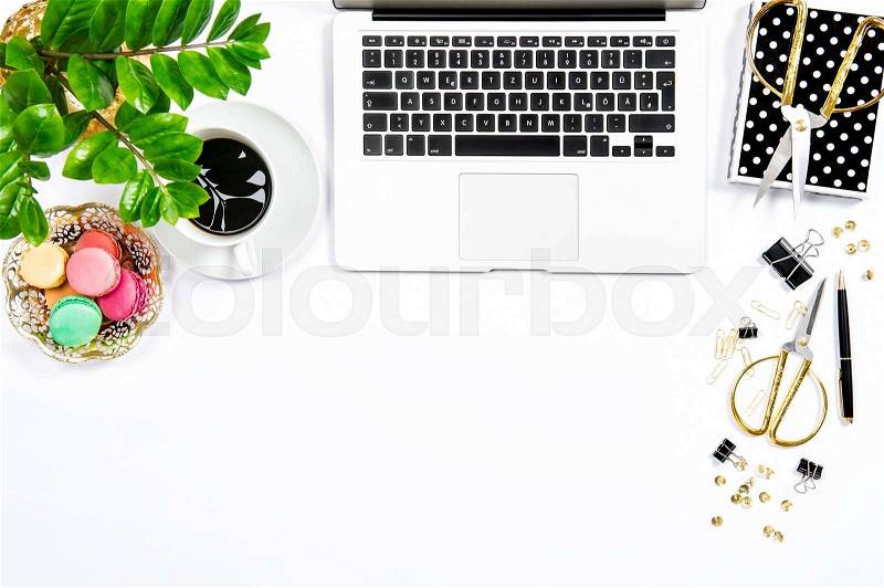 Feminine workplace. Coffee, macaroon cookies, office supplies, laptop computer and green plant on white table background. Top view. Flat lay, stock photo