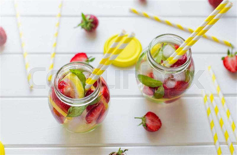 Two glasses withcocktail tubes. homemade strawberry lemonade, served with fresh strawberries, mint, lime and ice cubes, stock photo