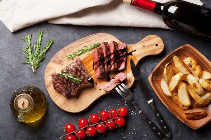 Grilled striploin steak with potato and red wine over stone table. Top view, stock photo