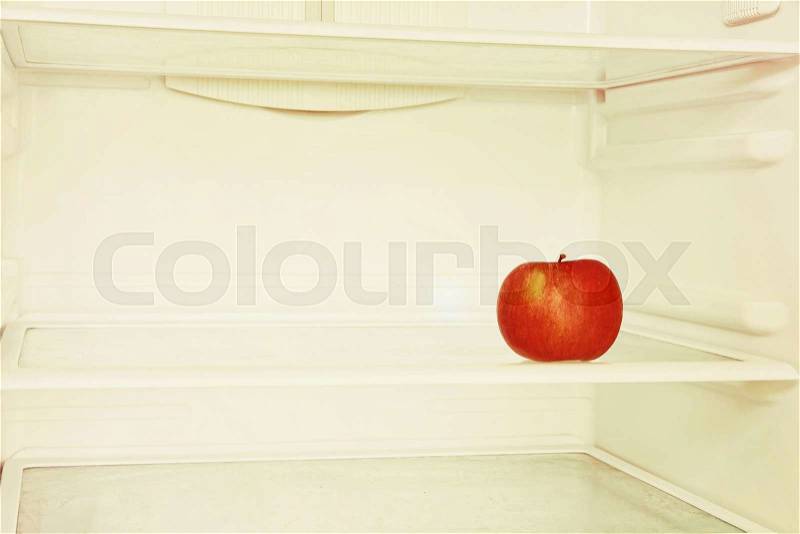 Single red apple in domestic refrigerator taken closeup. Toned image, stock photo