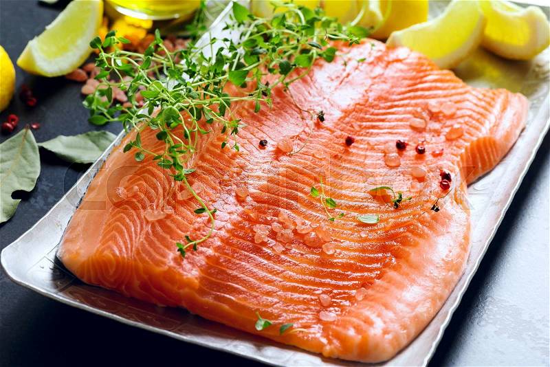 Raw salmon fillets on aluminium trey with lemon and spices, stock photo
