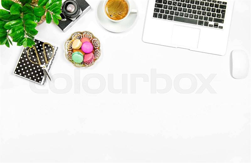 Creative feminine home office workplace. Coffee, macaroon cookies, laptop computer and green plant on white table background, stock photo