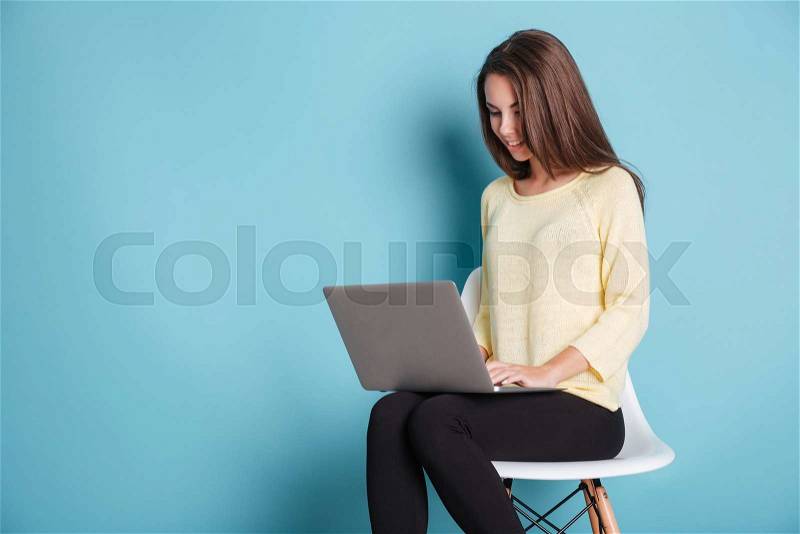 Young beautiful smart woman using laptop pc computer for study isolated on the blue background, stock photo
