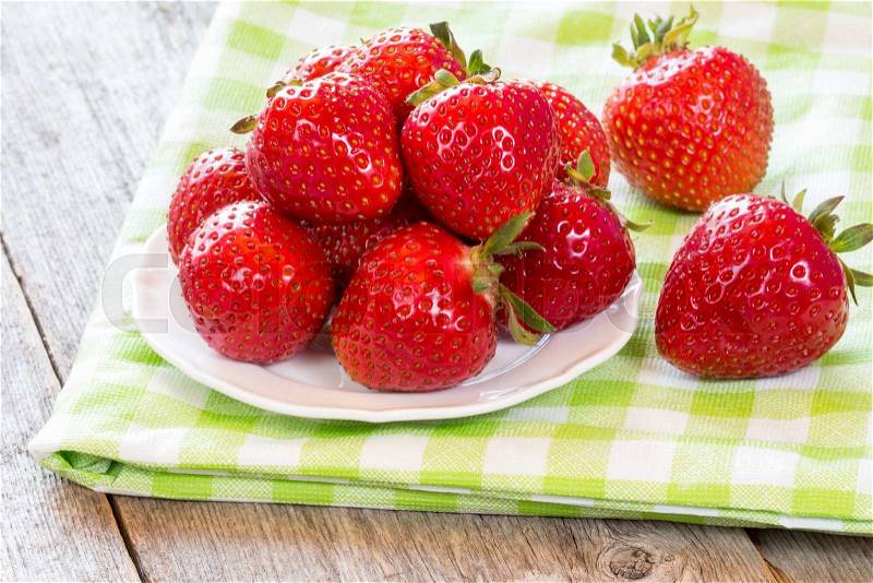 Plate with fresh strawberries on green and white checkered napkin, stock photo