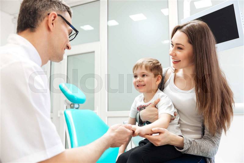 Smiling mother and her little son visiting dentist, stock photo