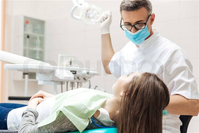 Dentist very carefully check up and repair tooth of his young female patient in the clinic, stock photo