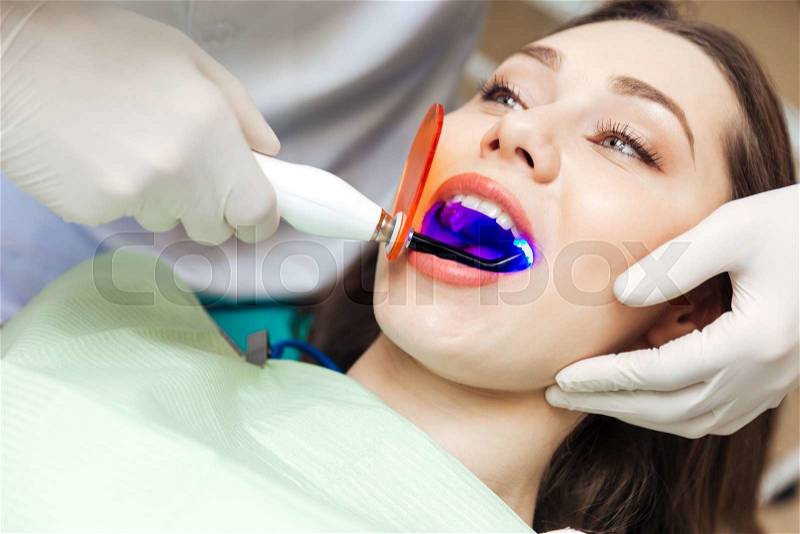 Close-up portrait of a female patient visiting dentist for teeth whitening in clinic, stock photo