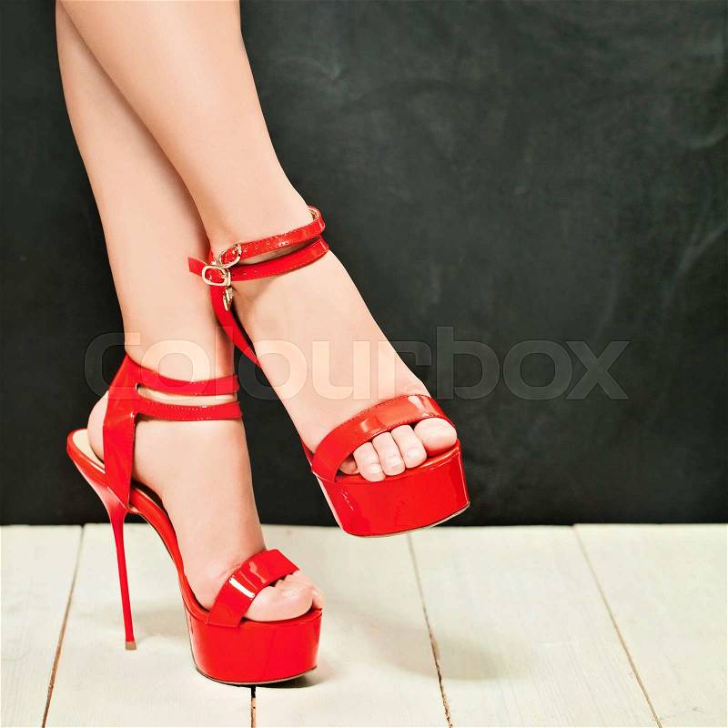 Woman Legs wearing High Heels Red Shoes on Dark. Fashion Background, stock photo