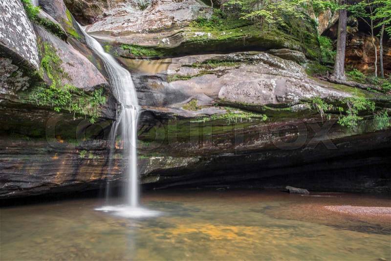 Cedar Falls, a beautiful waterfall in the Hocking Hills of Ohio, cascades down a sandstone cliff before finally plunging into a pool below, stock photo