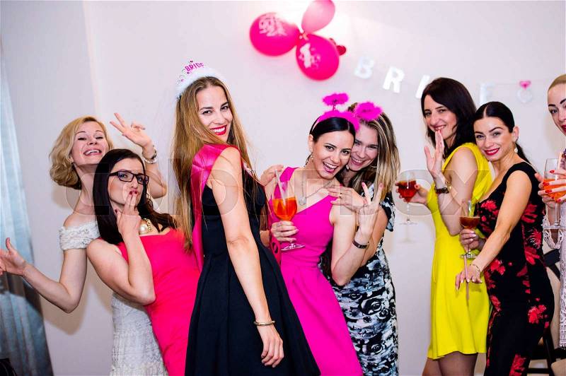 Cheerful bride and happy bridesmaids celebrating hen party with drinks. Women enjoying a bachelorette party dancing, stock photo