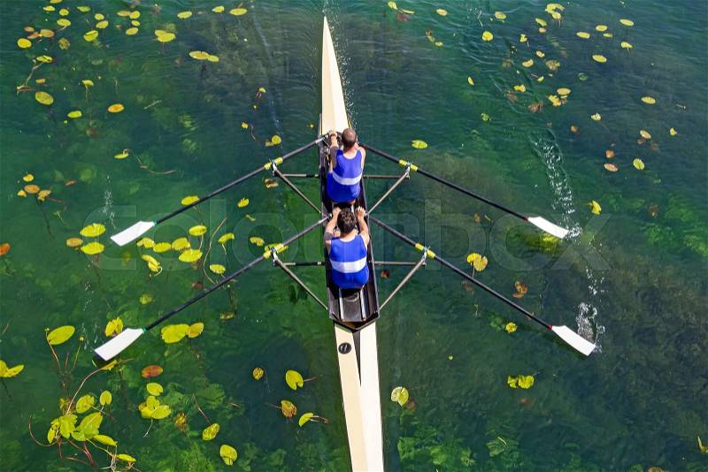 Two rowers in a boat, rowing on the tranquil lake , stock photo