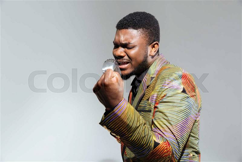 Handsome afro amerian man singing into vintage microphone isolated on a white background, stock photo