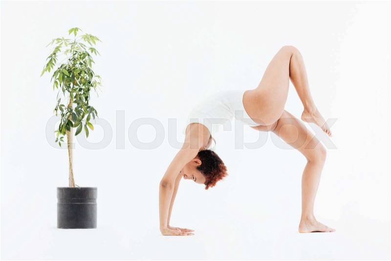 Attractive african american flexible woman doing backbend yoga pose, stock photo