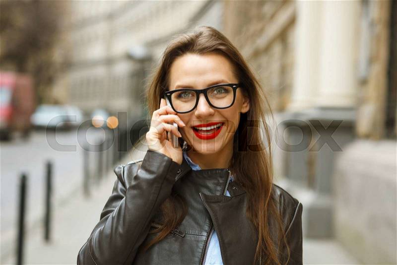 Businesswoman walking down the street while talking on smart phone. Happy smiling caucasian business woman busy, stock photo