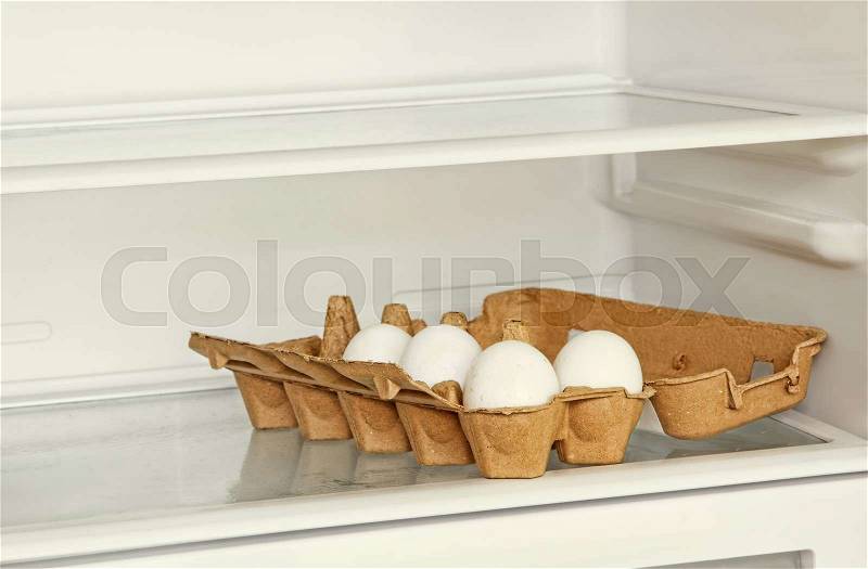 Fresh eggs in a paper box on refrigerator shelf taken closeup, stock photo