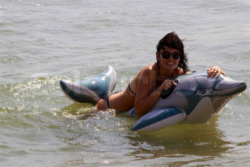 Woman floating in the sea on an inflatable dolphin. a photo, stock photo