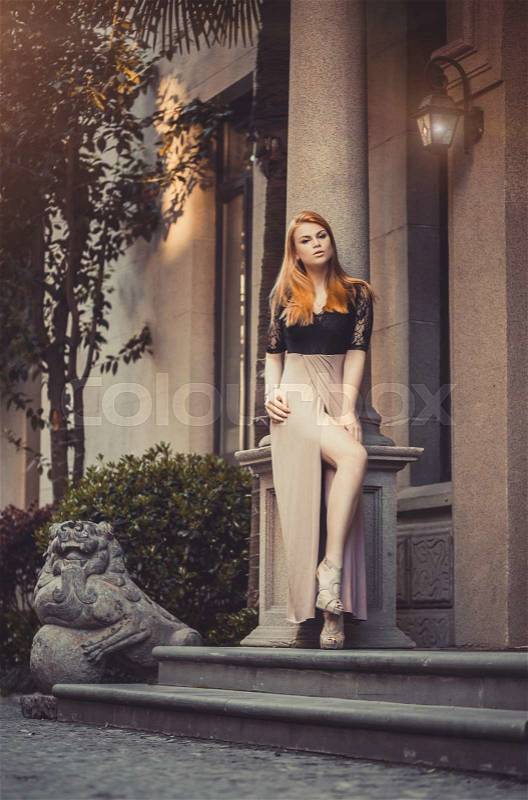 Beautiful Blond Red-haired woman girl model in old architecture environment with columns, stock photo