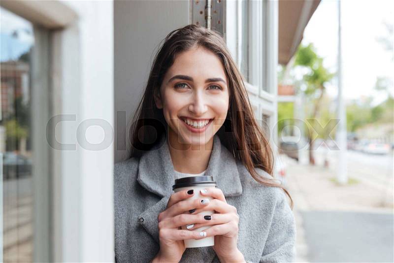 Happy cheerful smiling girl holding take away coffee and looking at camera at the restaurant, stock photo