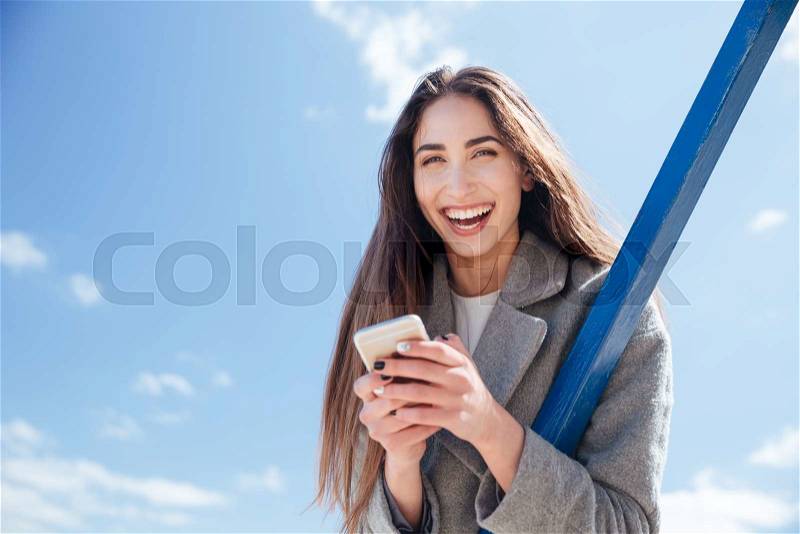 Young smiling beautiful woman holding camera to take a shot at the seaside, stock photo