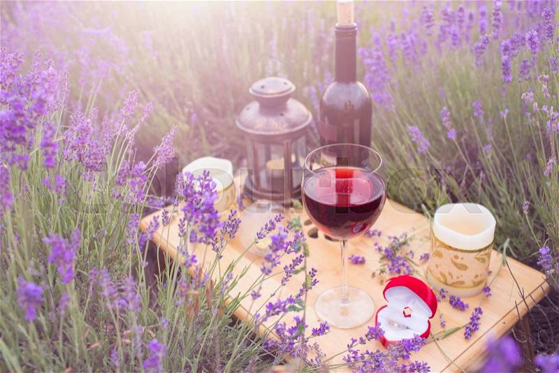 Small table with bottle of wine decorated for engagement in lavender field, stock photo
