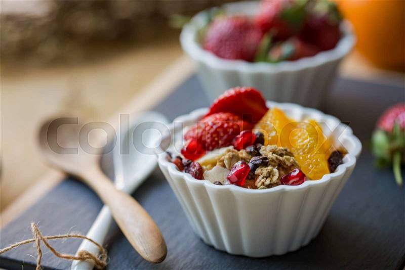 Granola with Orange, Strawberry, Cacao nibs and Pomegranate on yogurt, stock photo