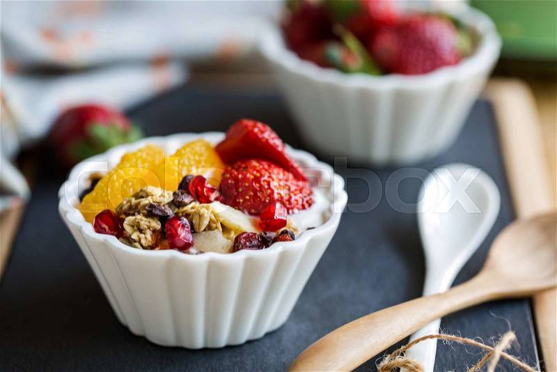 Granola with Orange, Strawberry, Cacao nibs and Pomegranate on yogurt, stock photo