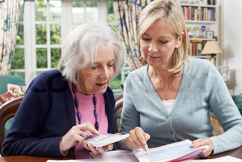 Mature Woman Helping Senior Neighbor With Home Finances, stock photo