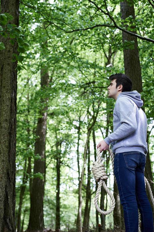 Depressed Man Contemplating Suicide By Hanging In Forest, stock photo