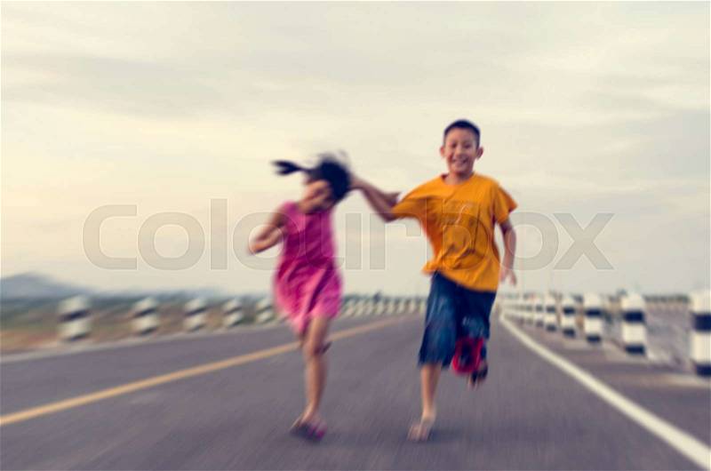Blurry background motion blur Girl and boy running, jumping outdoor on asphalt road, stock photo
