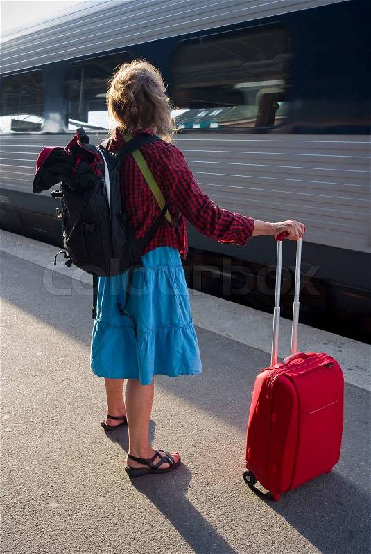 Danish woman with roller bag waiting on the platform for a train, stock photo