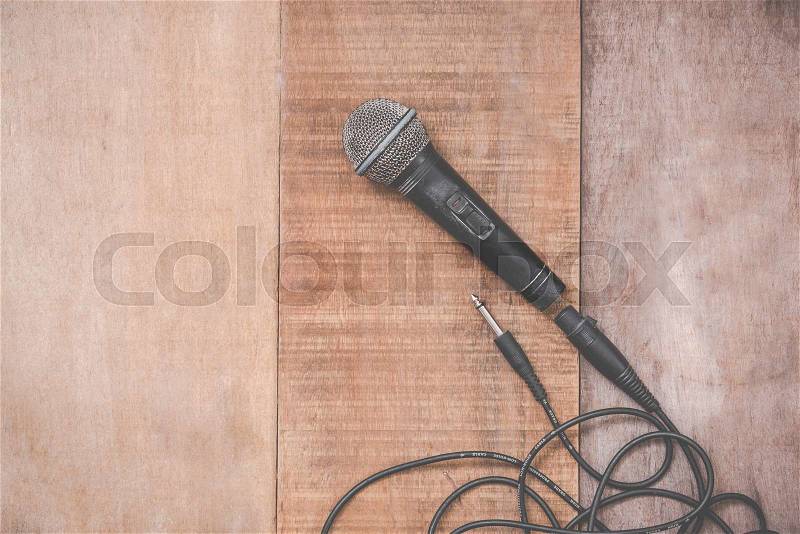 Grunge microphone with cable on wooden background, stock photo