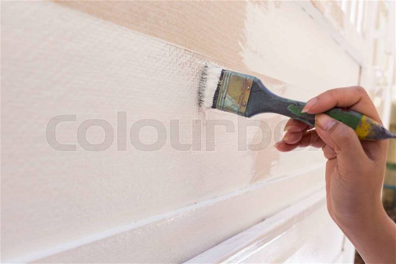Hand worker holding brush painting white on wood fence, stock photo