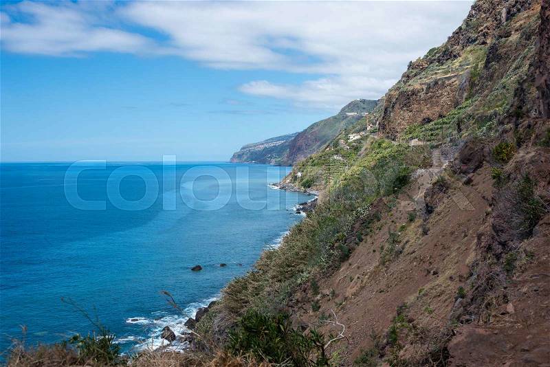The volcanic rocks of the east caost of madeira island with blue sky and green vegetation near calheta village, stock photo