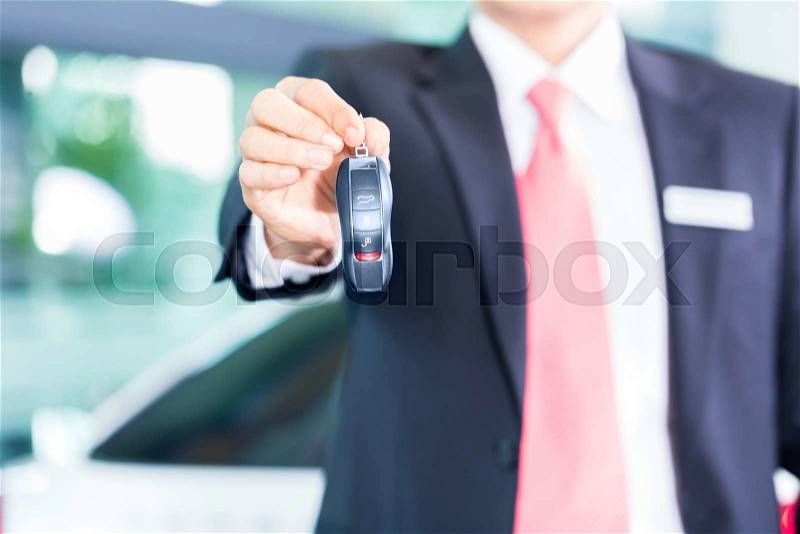 Car dealer handing over auto key, stock photo