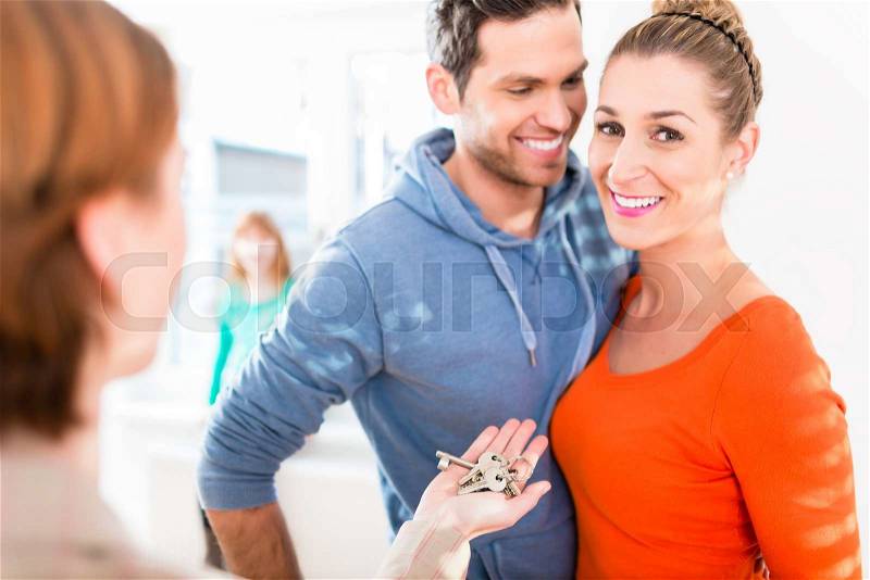 Accommodation broker giving home key to family, stock photo