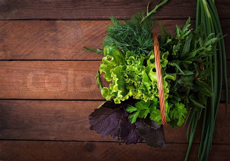 Variety fresh organic herbs (lettuce, arugula, dill, mint, red lettuce and onion) on wooden background in rustic style. Top view, stock photo