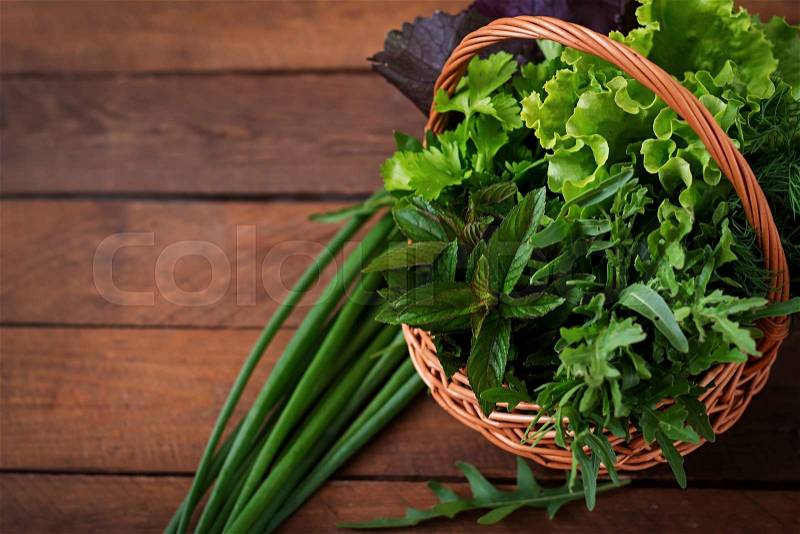 Variety fresh organic herbs (lettuce, arugula, dill, mint, red lettuce and onion) on wooden background in rustic style, stock photo