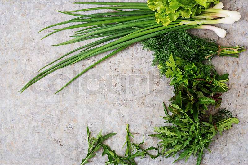 Variety fresh organic herbs (lettuce, arugula, dill, mint, red lettuce and onion) on grey background in rustic style. Top view, stock photo