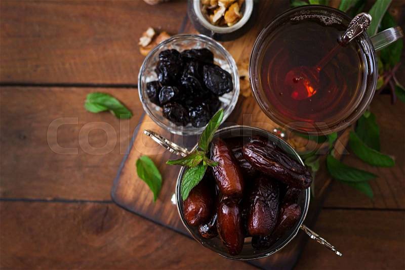 Mix dried fruits (date palm fruits, prunes, dried apricots, raisins) and nuts, and traditional Arabic tea. Ramadan (Ramazan) food. Top view, stock photo