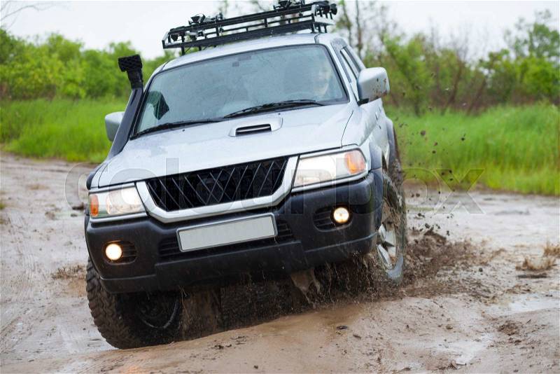Mitsubishi Pajero moving by water in the rain making lots of splashes, stock photo