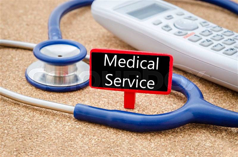 Phone and stethoscope on the table with Medical service words on the board. Medical concept, stock photo