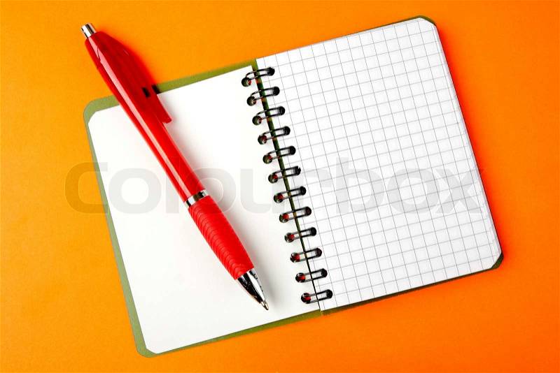 Opened notebook squared pagewith red pen over it on orange background, stock photo