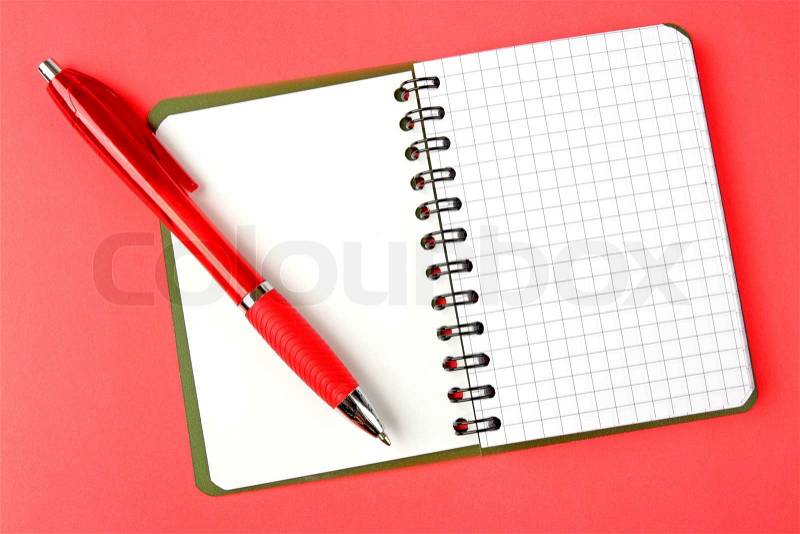 Opened notebook squared pagewith red pen over it on red background, stock photo