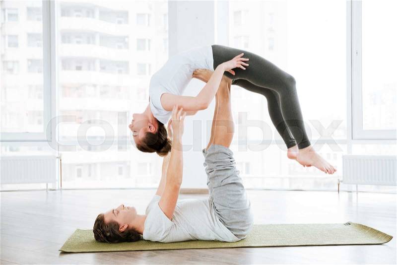 Peaceful couple balancing and doing acro yoga in studio, stock photo