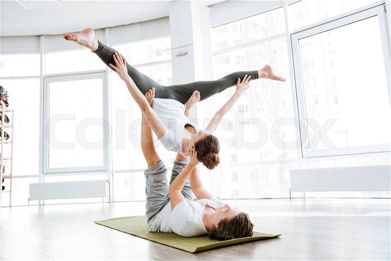 Beautiful couple doing flexibility workout in yoga studio together, stock photo