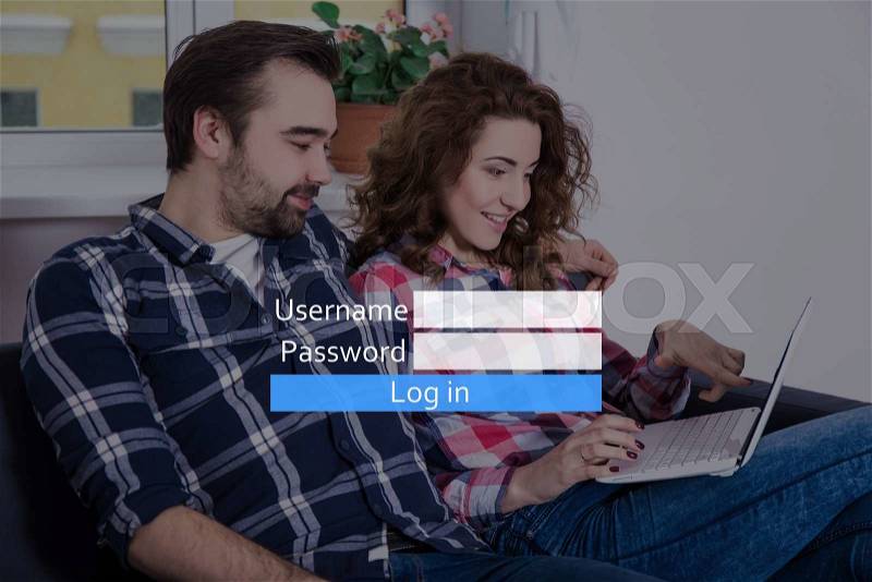 Online dating website concept - cheerful young couple using laptop at home, stock photo