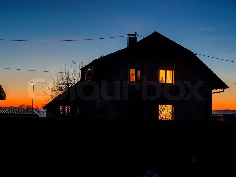 House at night with light in windows, stock photo