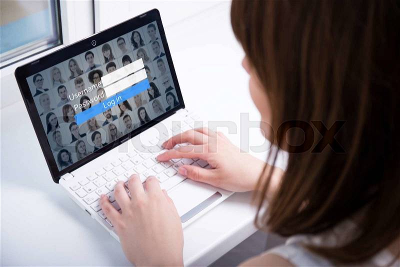 Back view of young woman using laptop with login box on screen, stock photo