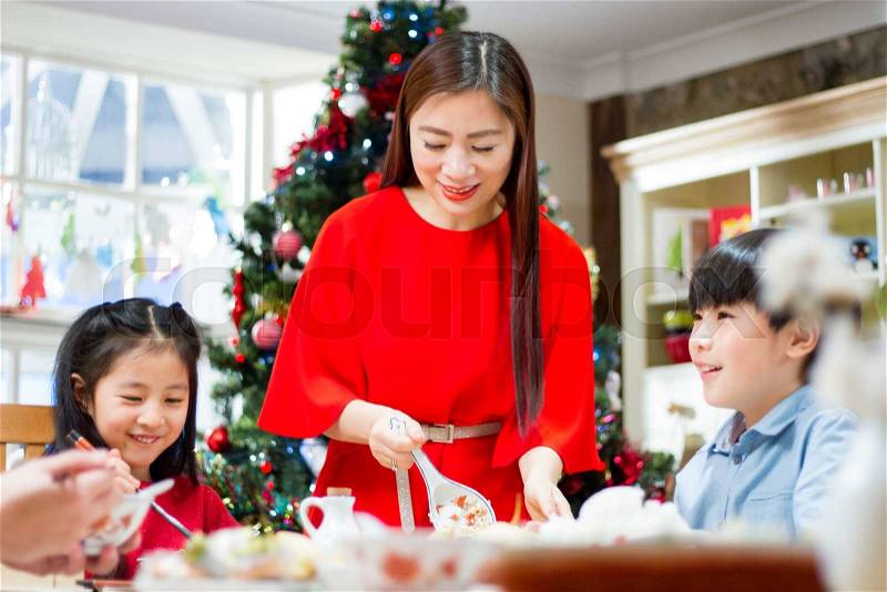 Chinese christmas dinner. The mother is dishing up rice to her children and partner who are sitting at the table. , stock photo