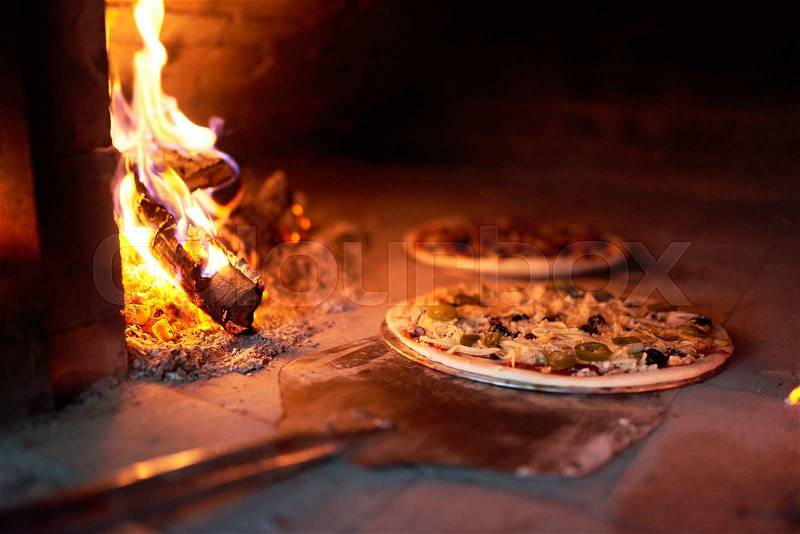 Raw pizza lay down the stove with the fire on the blade, stock photo